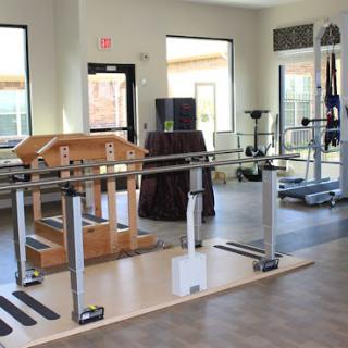 A well-equipped physical therapy room featuring parallel bars and other rehabilitation tools.