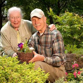 An elderly couple enjoys gardening together outdoors.