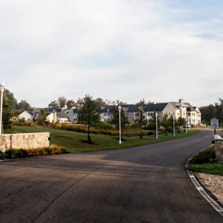 A quiet suburban neighborhood with neatly lined houses and streetlights along a winding road.