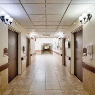 A well-lit hallway with multiple elevators and tiled flooring.