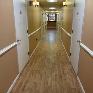 A long, empty hallway with wooden flooring and white doors on either side.