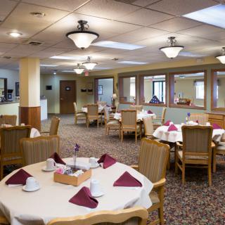 An elegantly set dining room with neatly arranged tables and chairs, featuring warm lighting and decor.