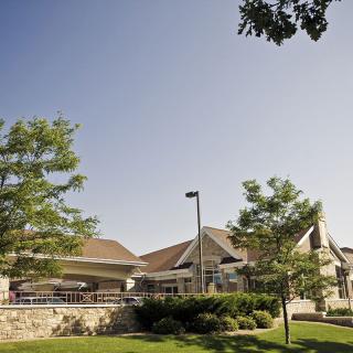 A picturesque view of a building surrounded by trees and lush greenery on a sunny day.