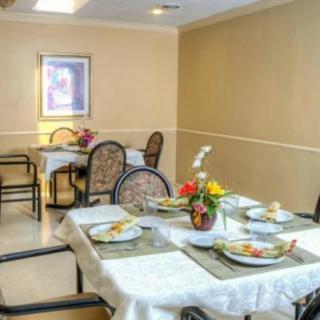 A cozy dining area with tables set for a meal, featuring floral centerpieces.