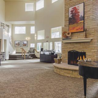 A spacious living room featuring a fireplace, grand piano, and large windows that let in natural light.