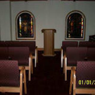 Interior view of a small chapel with seating and a podium.