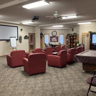 A conference room with red chairs arranged facing a projector screen and flip chart.
