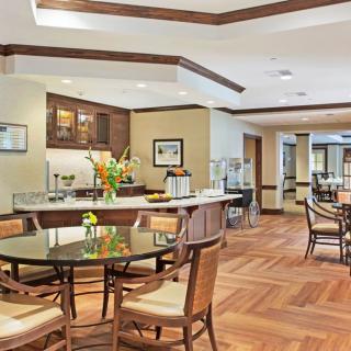 A spacious dining area with elegant furniture and wood flooring, featuring a buffet setup.