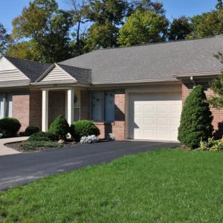 A suburban brick house with a well-maintained lawn and attached garage.