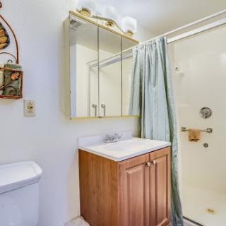 A compact and functional bathroom featuring a shower, vanity with mirror, and storage.