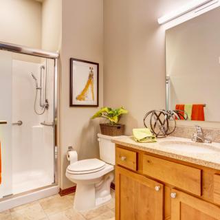 A modern bathroom featuring a glass shower, wooden cabinets, and bright lighting.