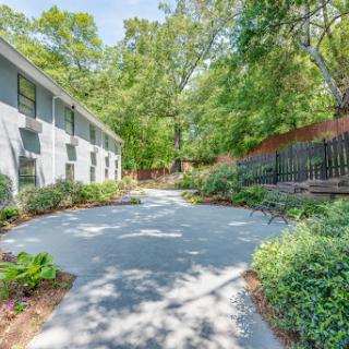 A serene pathway bordered by lush greenery and a modern building.
