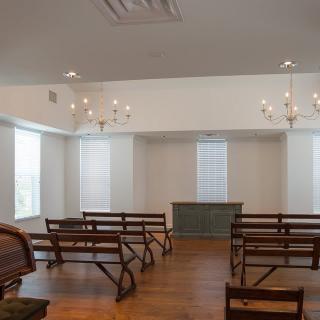 A minimalist chapel interior with simple wooden benches and elegant chandeliers.