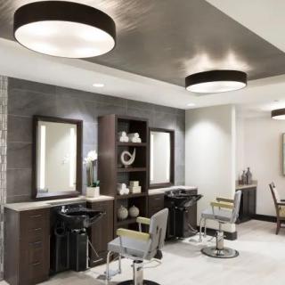 A modern salon interior with stylish chairs and mirrors, featuring sleek lighting and elegant decor.