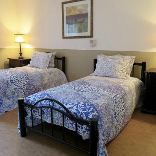 A cozy bedroom with two twin beds adorned with patterned bedding and lit by a bedside lamp.