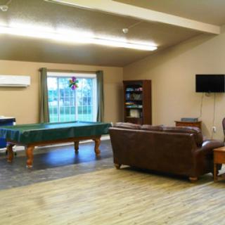 A cozy game room with a pool table, sofa, and television.
