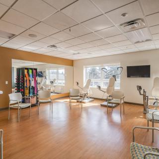 A bright and spacious waiting room with chairs, a television, and a vending machine.