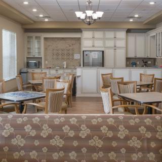A spacious kitchen and dining area with multiple tables and chairs, featuring elegant lighting and cabinetry.