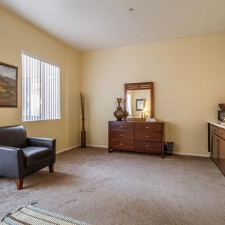 A cozy living room with an armchair and a dresser adorned with decor.