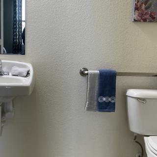 A small bathroom with a sink, mirror, toilet, and a towel hanging on a rack.
