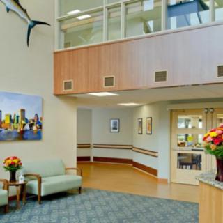 A well-lit lobby area with comfortable seating, decorative flowers, and artwork on the walls.
