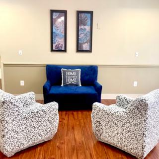 A cozy seating area featuring two patterned chairs and a blue sofa, perfect for relaxation and conversation.