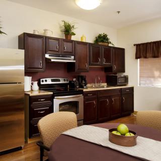 A modern kitchen with dark wood cabinets, stainless steel appliances, and a dining area.