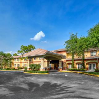A sunny day view of a hotel entrance surrounded by trees.