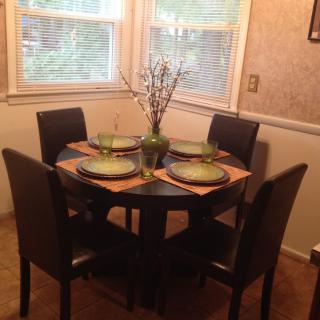 A cozy dining area with a round table set for four, featuring elegant decor and natural light from the windows.