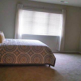 A minimalist bedroom with a large window and a neatly made bed.