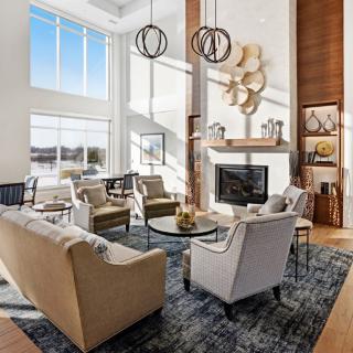 A modern living room with high ceilings, large windows, and contemporary furniture centered around a fireplace.