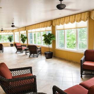A spacious sunroom with comfortable seating, large windows, and ceiling fans.