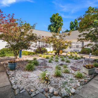 A well-maintained garden with shrubs and trees in front of a residential house.