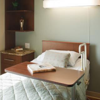 A serene hospital patient room featuring a comfortable bed and essential medical furnishings.
