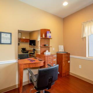 A small office space featuring a desk, chair, and shelves.