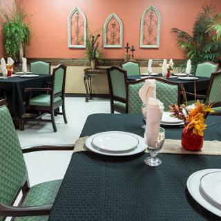 A well-arranged dining room featuring tables with elegant table settings and decorative plants.