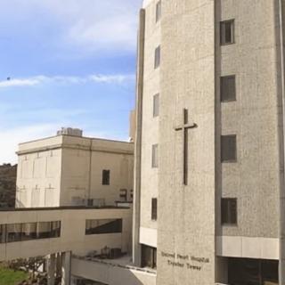 A hospital building featuring a prominent cross on its facade.