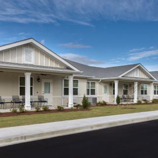 A row of single-story suburban houses with front porches under a clear blue sky.