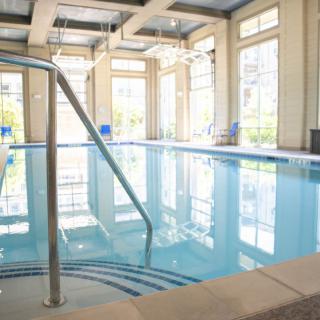 A bright indoor swimming pool surrounded by large windows.