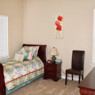 A cozy bedroom with a single bed, colorful bedding, and classic furniture.