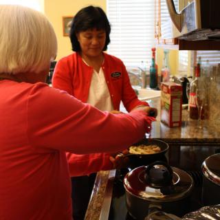 Two people cooking together in a kitchen setting.