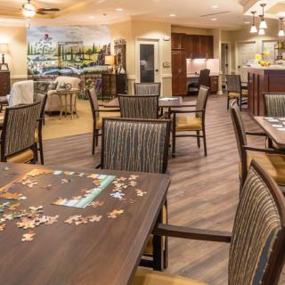 A cozy dining area with empty tables and chairs, featuring a puzzle laid out on one of the tables.