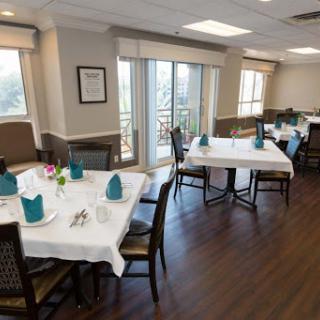 An elegantly arranged dining area with tables set for guests, complemented by natural lighting and tasteful decor.