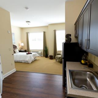 A cozy studio apartment with a kitchenette and a well-lit bedroom area.