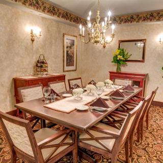 A formal dining room with an elegantly set table and a chandelier overhead.