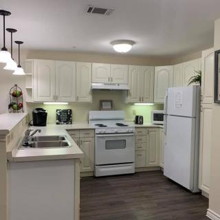 A modern kitchen featuring white cabinets, a refrigerator, stove, and sink with stylish pendant lighting.