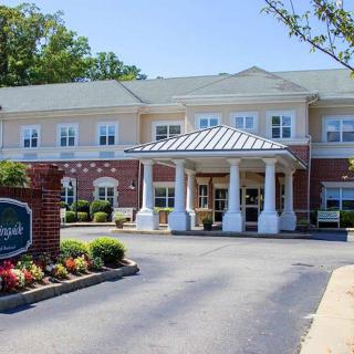 A modern building with a welcoming entrance, featuring white columns and landscaped surroundings.