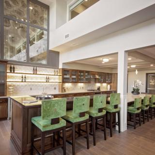 Modern kitchen with green bar stools and open design.