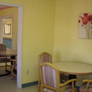A cozy room with yellow walls, featuring a round table and chairs, adorned with artwork.