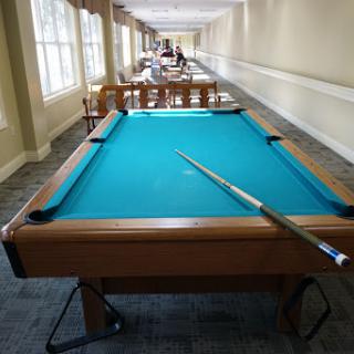 A well-lit game room featuring a blue felt pool table ready for a game.